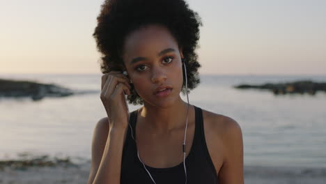 portrait of fit african american woman looking to camera puts on earphones listening to music