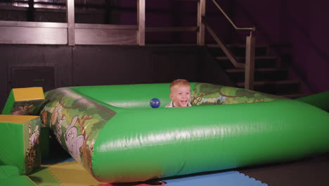 young happy boy jumping in to a ball pit