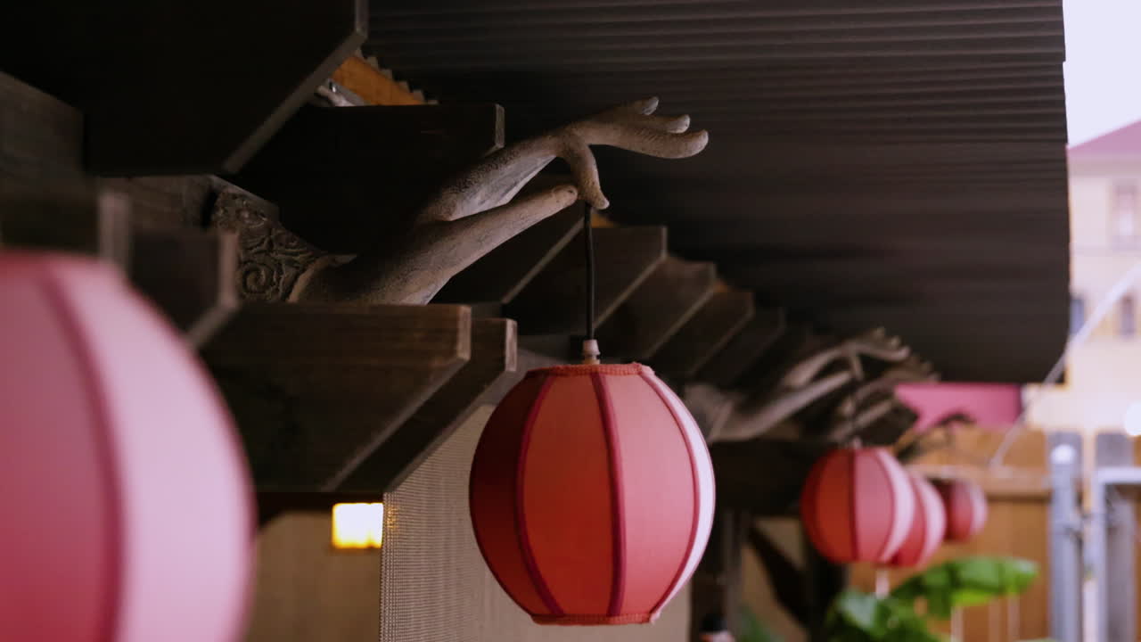 Closeup of Red Lanterns Hanging from a Wooden Structure with Hand Sculptures