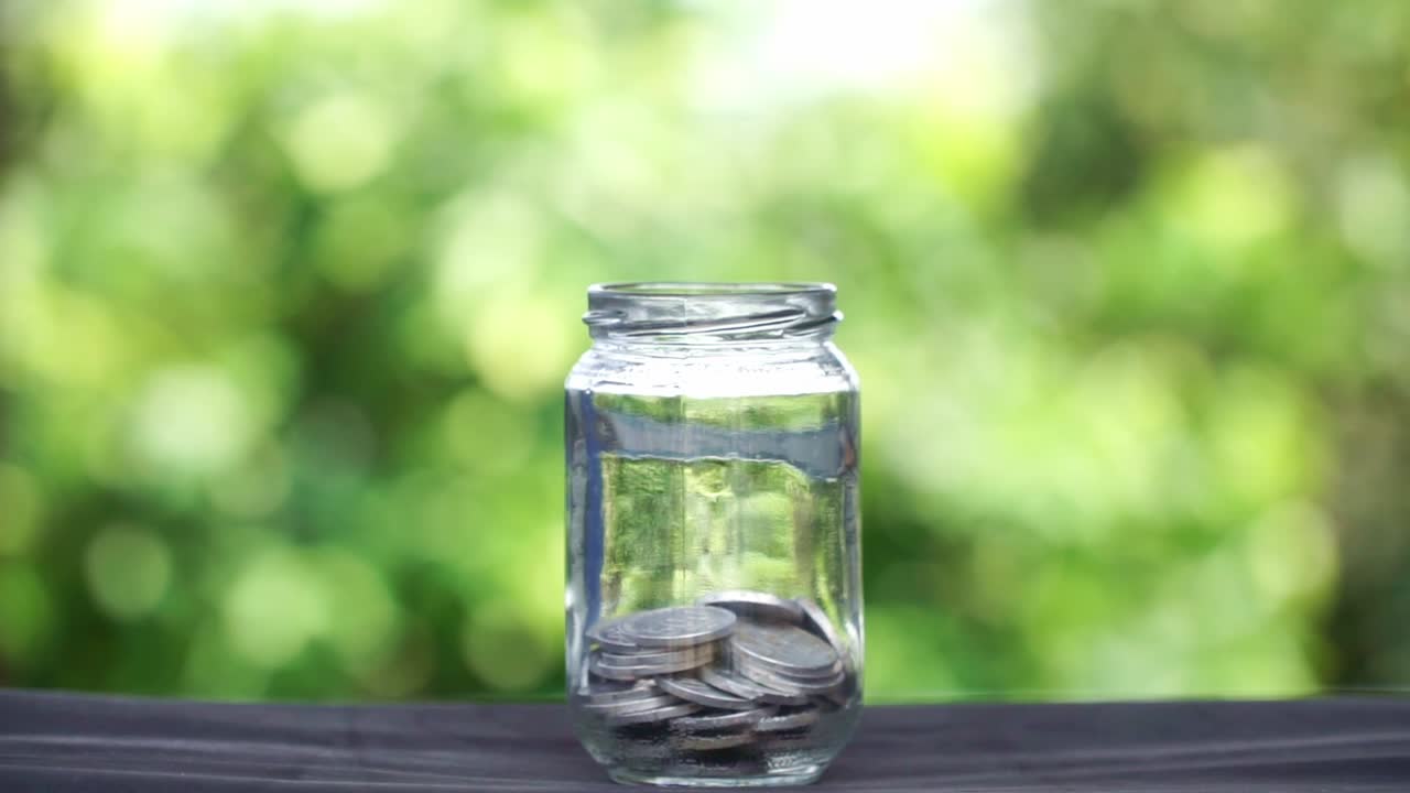 ボケ背景のガラス瓶に貯金された硬貨