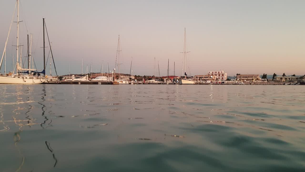 punto de vista de la superficie del agua de ángulo bajo del barco que regresa al puerto por la noche