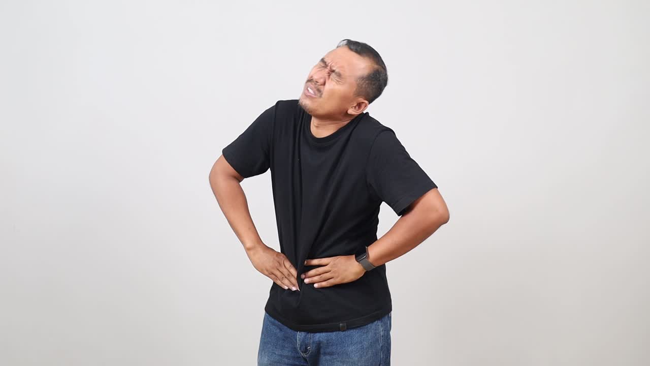 Asian man touching his stomach isolated on white background. Abdominal pain or ache concept