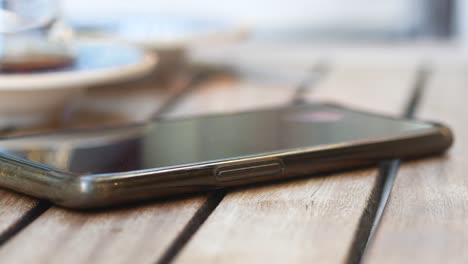 close up of a black phone on a wooden table