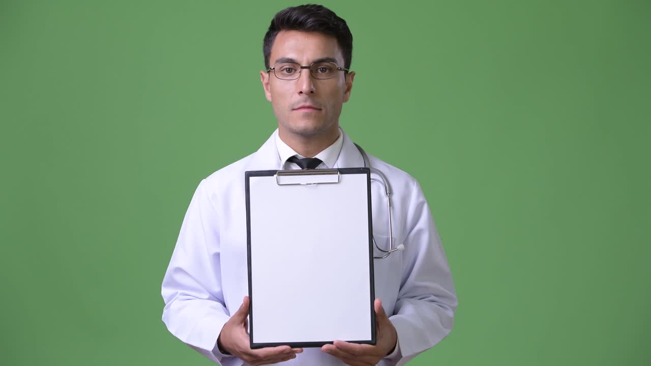 Genç yakışıklı Hispanik erkek doktor yeşil arka plan önünde.