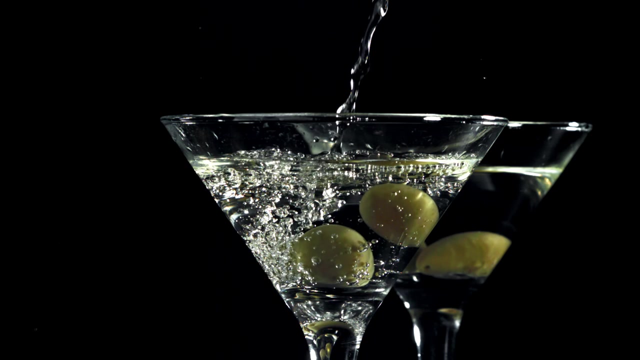 Movimento rallentato del versamento di Martini in un bicchiere con olive