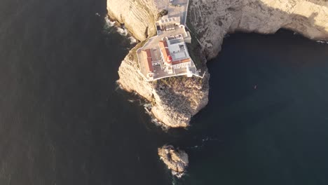 Birds-eye-view-of-the-lighthouse-in-Sagres,-Portugal-located-on-a-small-peninsula-surrounded-by-steep-cliffs