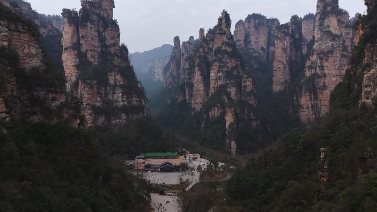 A bus station set against the towering sandstone pillars of Zhangjiajie, providing travelers with a unique transit hub surrounded by breathtaking mountain landscapes and lush greenery.