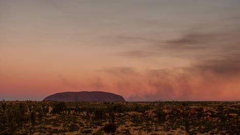 a time lapse of smoke from controlled bush fires blowing around uluru in the northern territory, australia