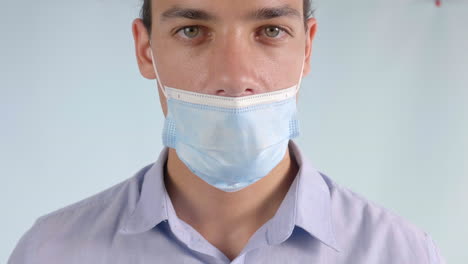 man wearing surgical mask below nose incorrectly, closeup looking at camera