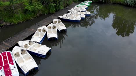 pedal boats moored in row by the wooden jetty on the lakeside at daytime