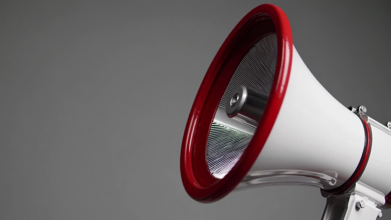 Close-up video of a red and white megaphone against a gray background, shot from a side angle