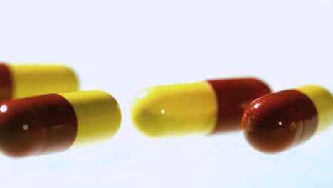 red and yellow capsule tablets falling and bouncing close up