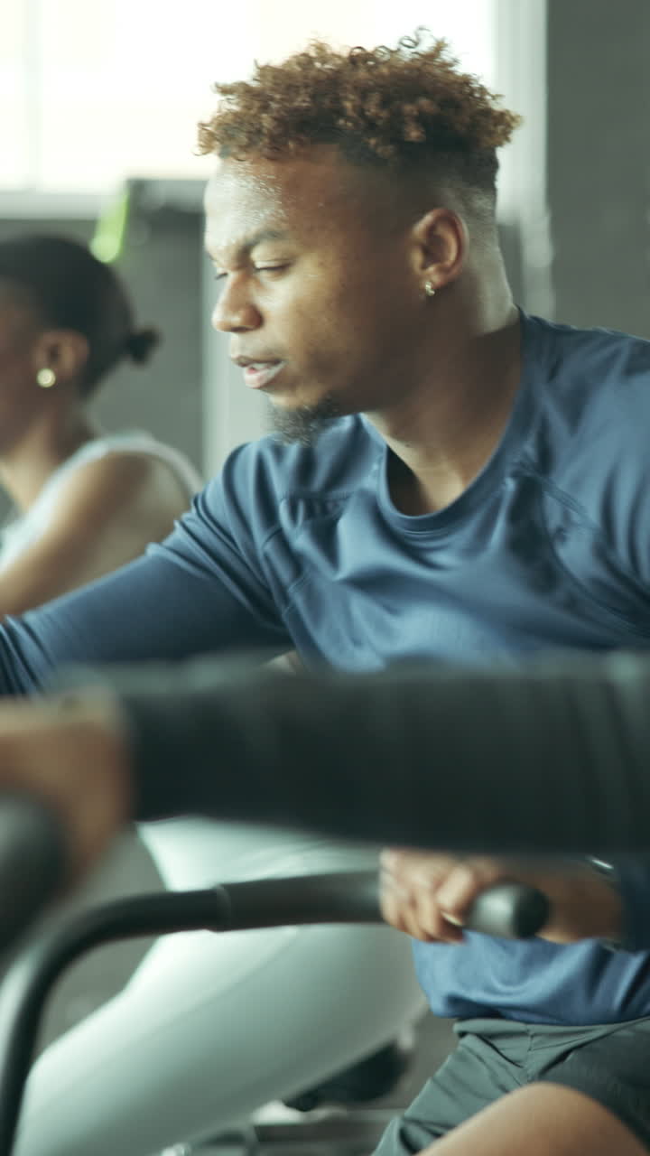 Man and Woman Exercising on Stationary Bikes in a Gym