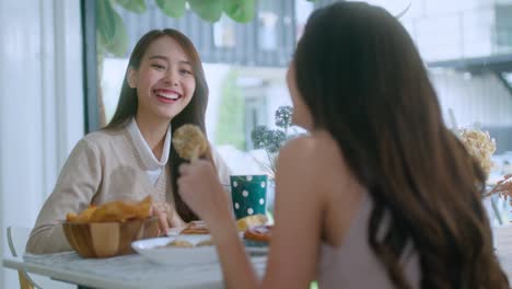 매력적인 아시아 여성은 미소 짓고 웃으며 친구들과 좋은 긍정적 인 대화를 나누고 카페의 창문 근처의 카운터에서 정원에서 낮빛으로 긍정적인 태도 관계를 유지합니다.