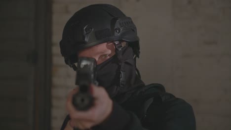 swat police officer pointing a gun at the camera with police lights flashing at a protest