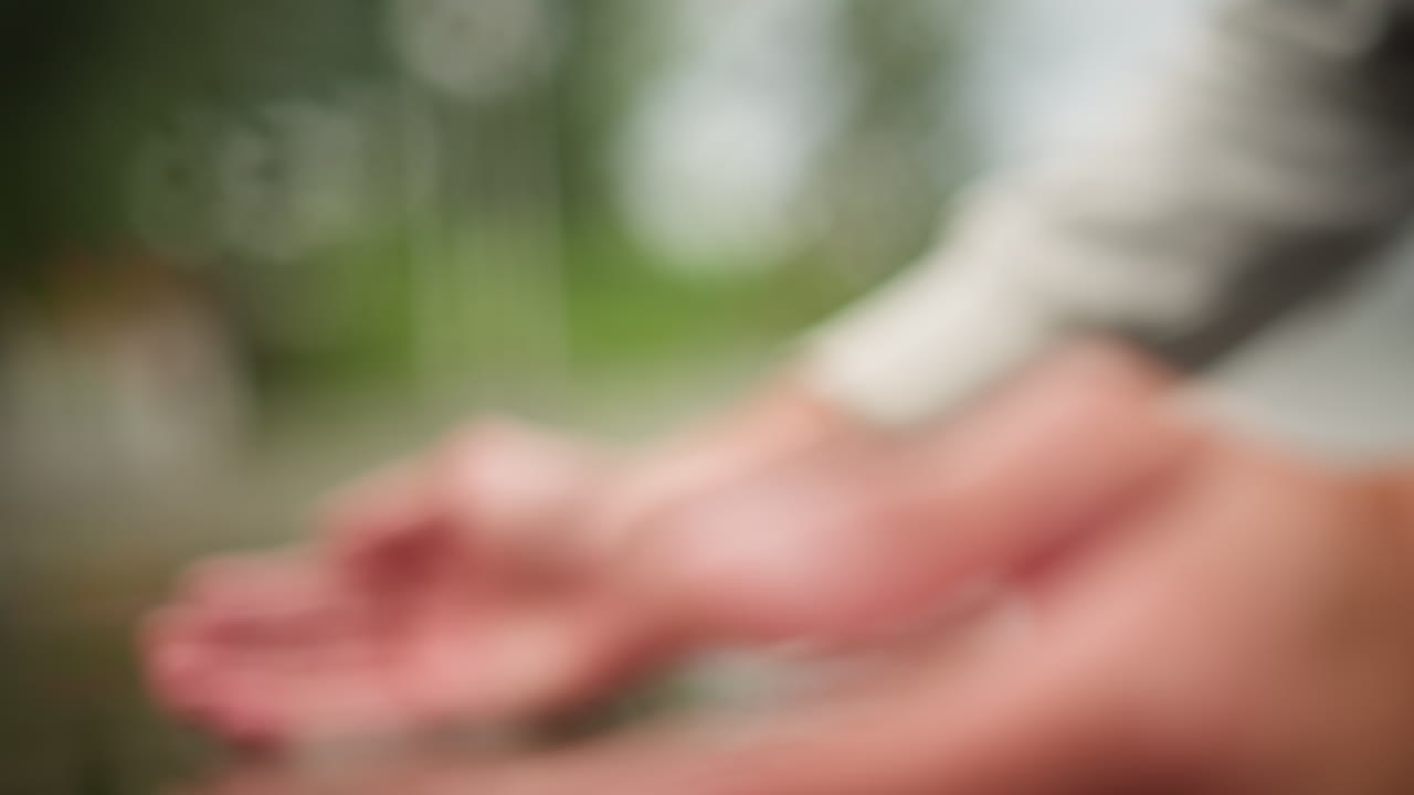 Palms holding water in serene park, Gentle hand positioning gathering rainwater amidst natural surroundings, Focused view of palms collecting fountain water in tranquil park environment