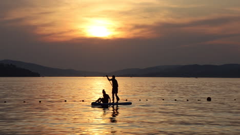 Silueta-Al-Atardecer-Pareja-Activa-Remando-De-Pie-En-Una-Bahía-Tropical