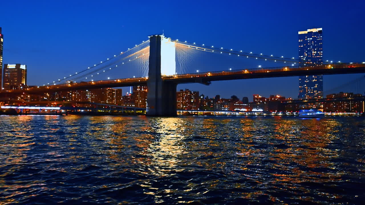 Giro in battello notturno con vista mozzafiato sulla splendida New York. Avvicinamento al Ponte di Brooklyn ben illuminato con auto in movimento
