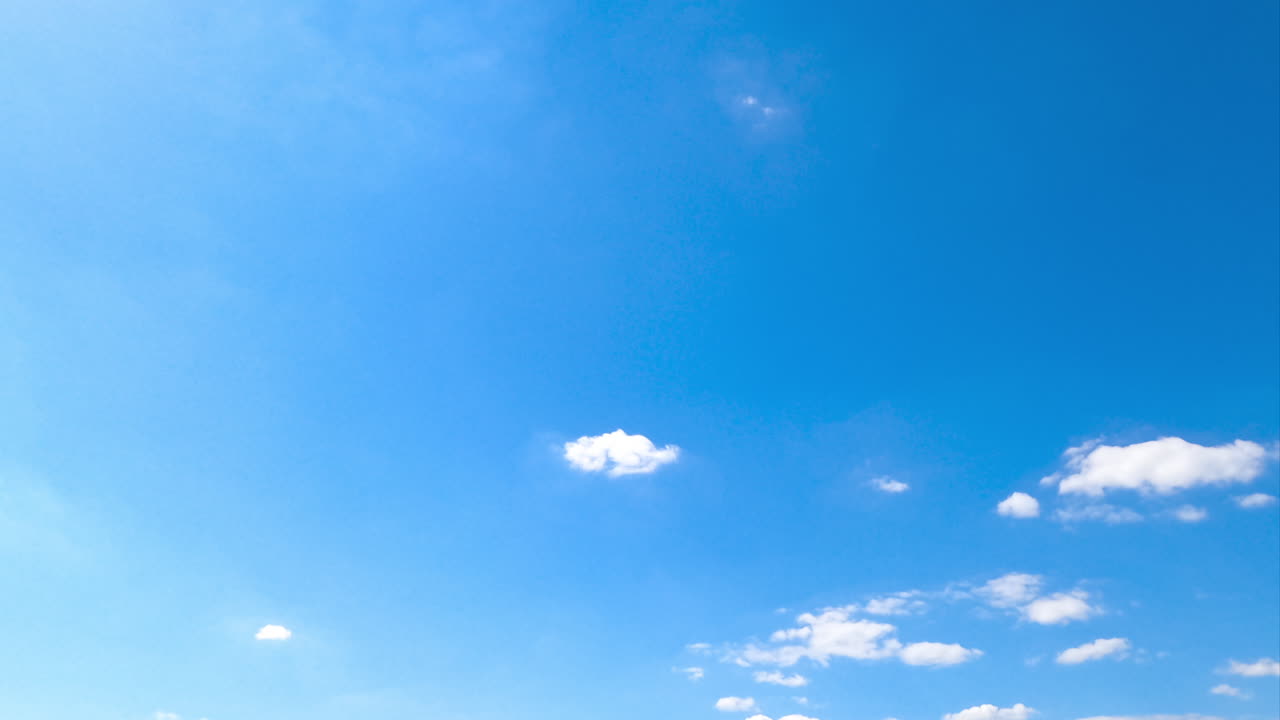 Tiny light cotton clouds appearing in the sky. Beautiful summer sky with sunbeams. Timelapse.