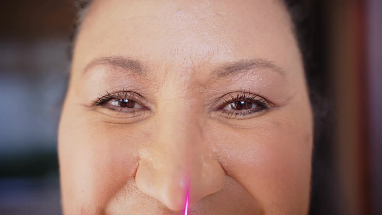 Mature woman squinting then opening eyes as neon beams sweeping face, showing eyeliner for beauty
