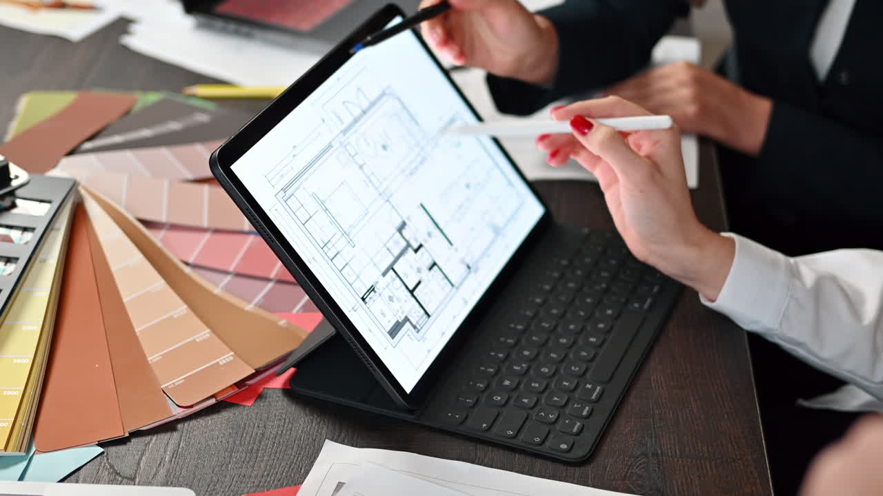Coworkers analyzing a building plan on a tablet at a table in an office