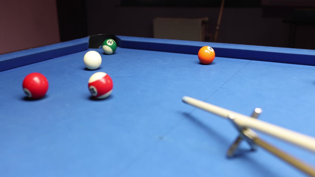 Persoon raakt een witte bal, voorovergebogen boven een blauwe biljarttafel.