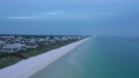 drone view flying from the beach over the gulf of mexico looking towards rosemary florida during golden hour sunset