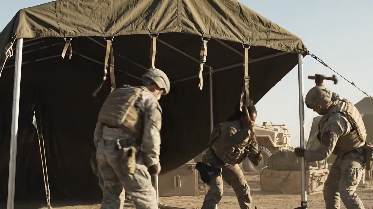 Soldati che collaborano per montare una tenda tattica durante un'operazione militare in terreno desertico, dimostrando lavoro di squadra e prontezza in condizioni difficili.