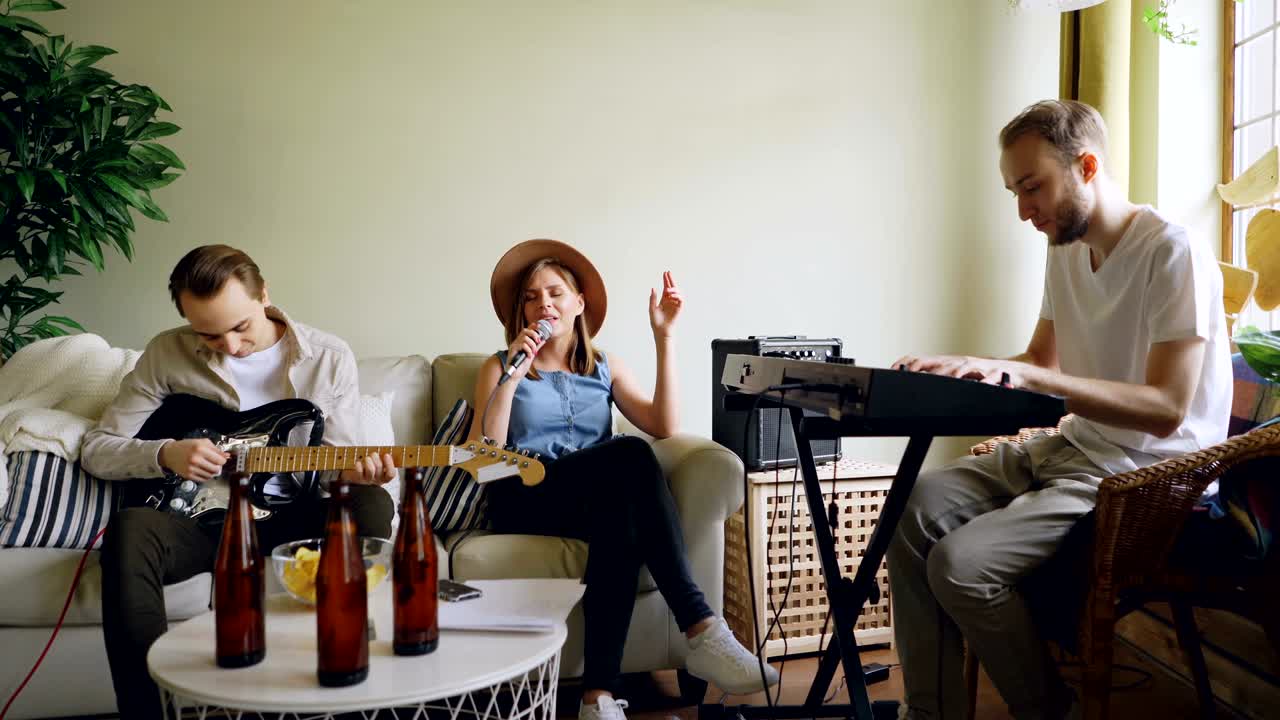 인기 있는 뮤지컬 그룹이 집에서 리허설을 하고 있다. 예쁜 금발 여자가 노래를 부르고, 즐거운 젊은 남자들이 기타와 키보드를 연주하고 있다.