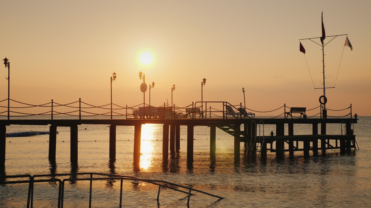 물속으로 튀어나온 부두의 바다 실루엣 위로 새벽 - 여름의 경치 좋은 풍경