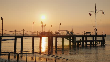 dawn over the sea silhouette of a pier that protrudes into the water - a scenic landscape of summer