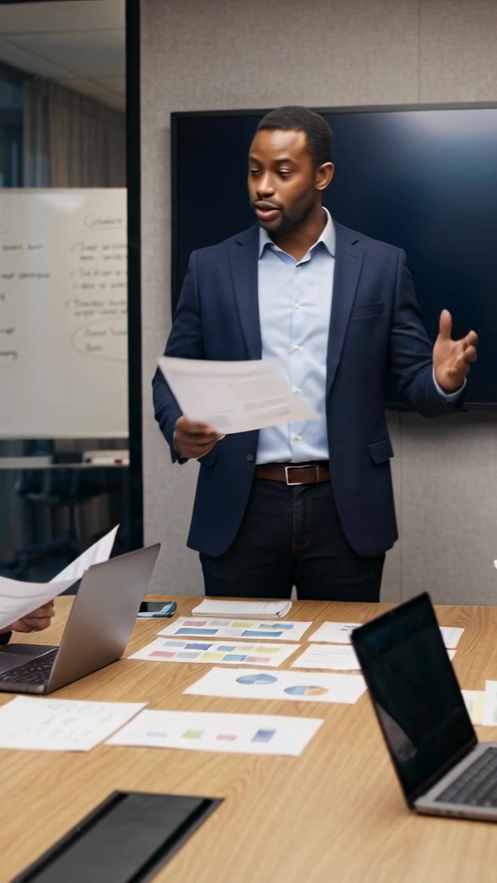 Video verticale: Riunione che inizia, manager in abito che indica grafici in ufficio mentre esamina i dati.