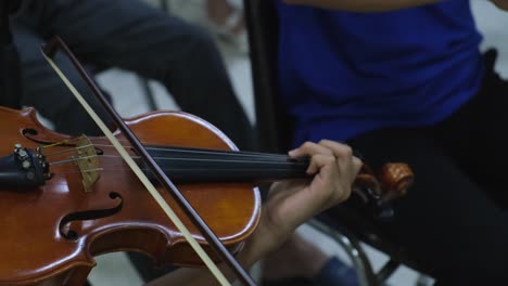 manos tocando el violín, inclinándose arriba y abajo y los dedos de la mano izquierda atacando las notas, violinista