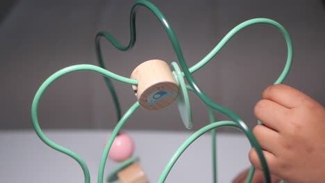 child's hand playing with a colorful wooden maze toy