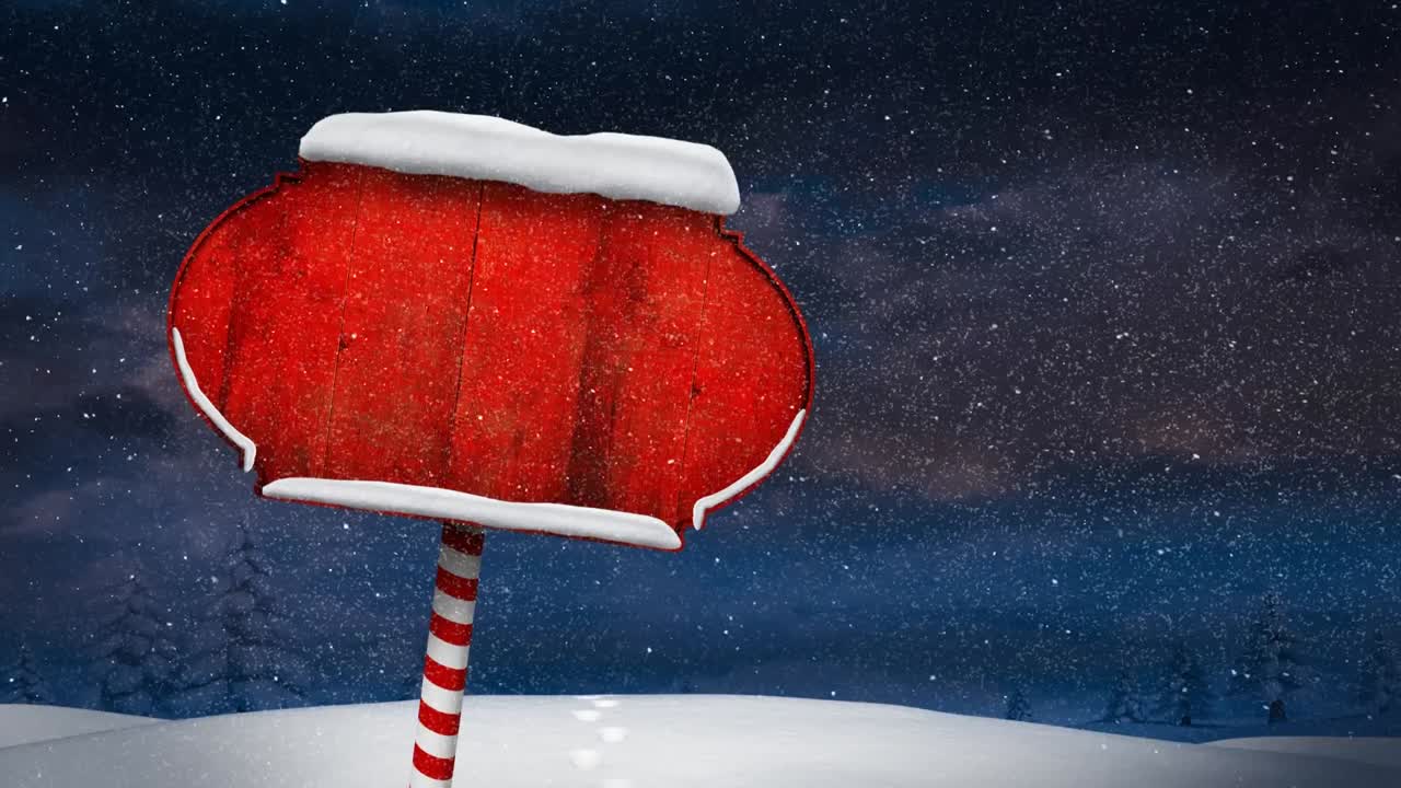 Snow falling over red wooden sign post on winter landscape against night sky