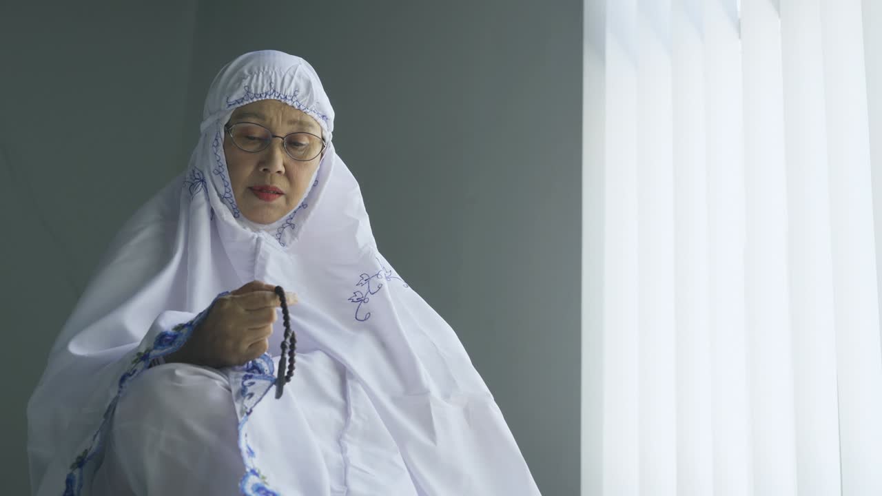 пожилая женщина держит бусы для дхикра после молитвы