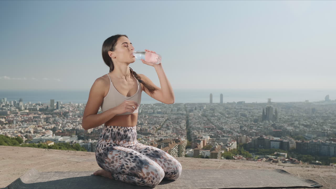 Donna che apre una bottiglia d'acqua all'aperto. Ragazza che beve acqua al punto panoramico.