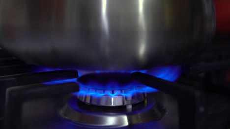 the kettle is removed from the stove closeup. they take the kettle off the fire and turn off the gas stove. the flame is blue.