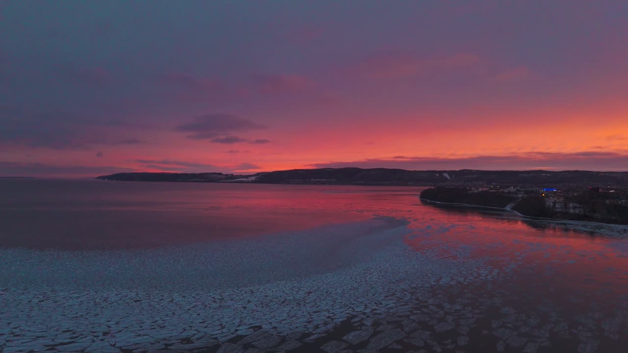 Vibrant sunset over Skjalfandi Bay in Husavik Iceland with glowing sky reflecting on calm sea and coastal town silhouette, scenic Nordic landscape at dusk