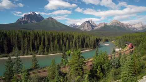 red cargo train passing through morant's curve in bow valley, banff national park, alberta, canada, iconic landscape and railway system in the canadian rocky mountains