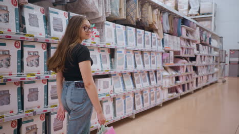 dama caminando por el pasillo del supermercado, mirando los productos de cama en los estantes, tienda llena de cubiertas de edredón y mantas de cama, ambiente minorista brillante con mercancías bien dispuestas