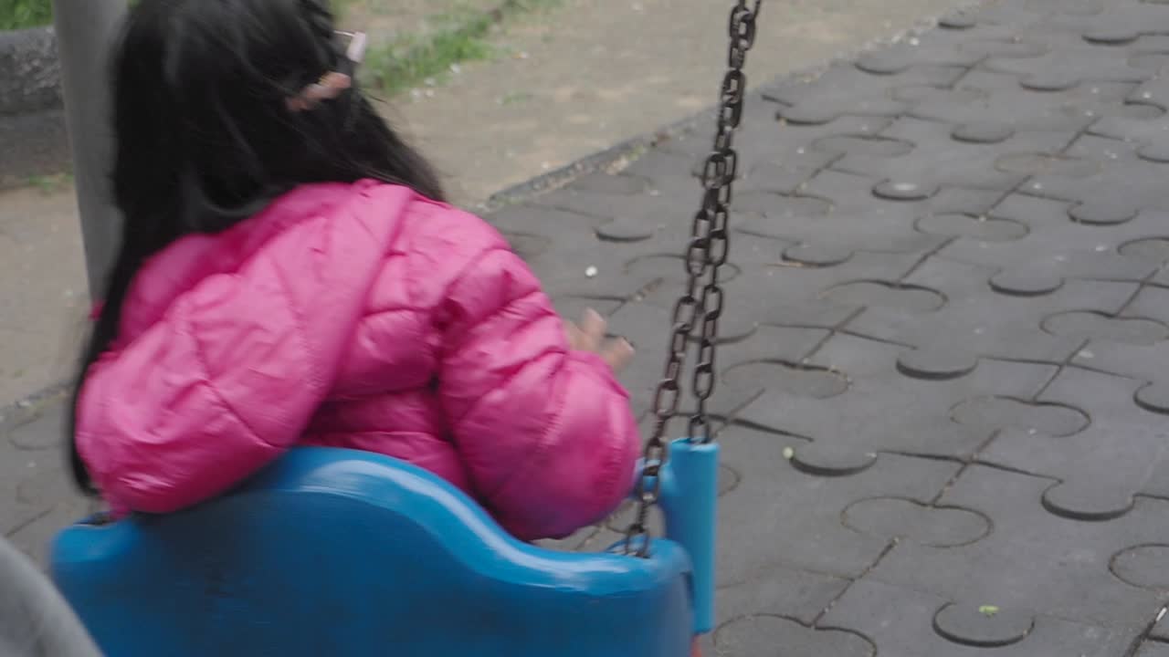 chica en un columpio en un parque con pavimentación de rompecabezas