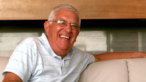 Senior-man-smiling-at-camera-on-couch