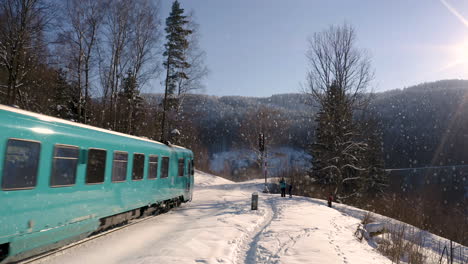 Family-waiting-at-railway-signal-in-falling-snow-for-a-train-to-pass