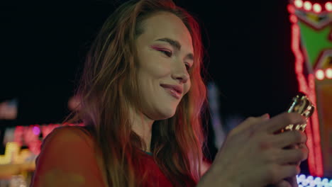 smiling girl swiping mobile phone on night street closeup. relaxed woman surfing