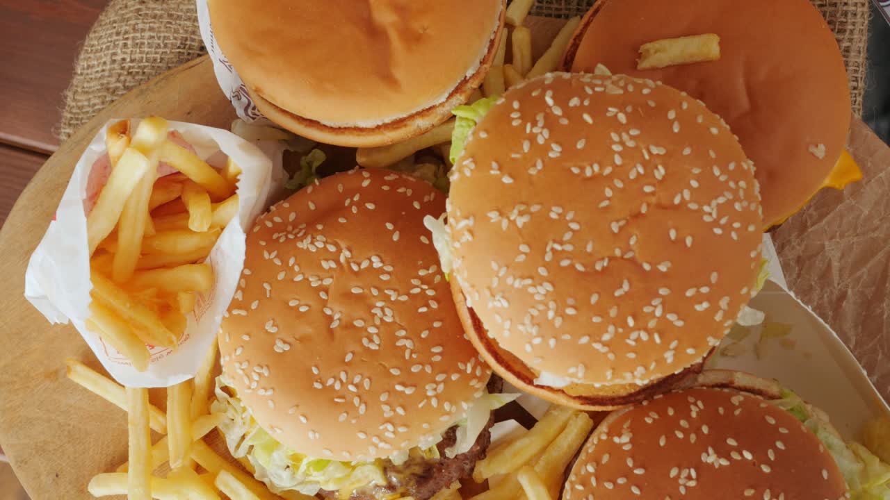 porción de comida no saludable, comida rápida, pila de hamburguesas, patatas fritas girando, vista desde arriba