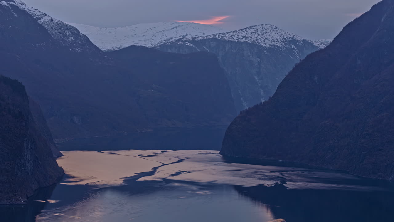 Timelapse di uno splendido paesaggio norvegese del lago Lovatnet con giochi di luce e ombra che cambiano e montagna innevata sullo sfondo.