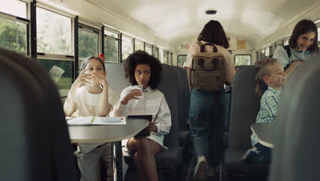 multicultural students sitting school bus in morning. pupils boarded schoolbus.