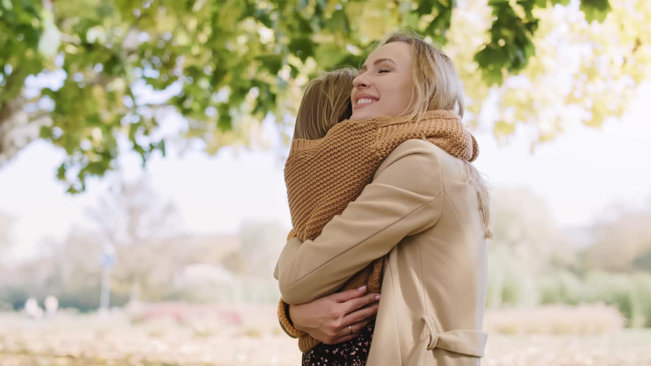 행복한 작은 소녀가 엄마를 포옹하고 있습니다.