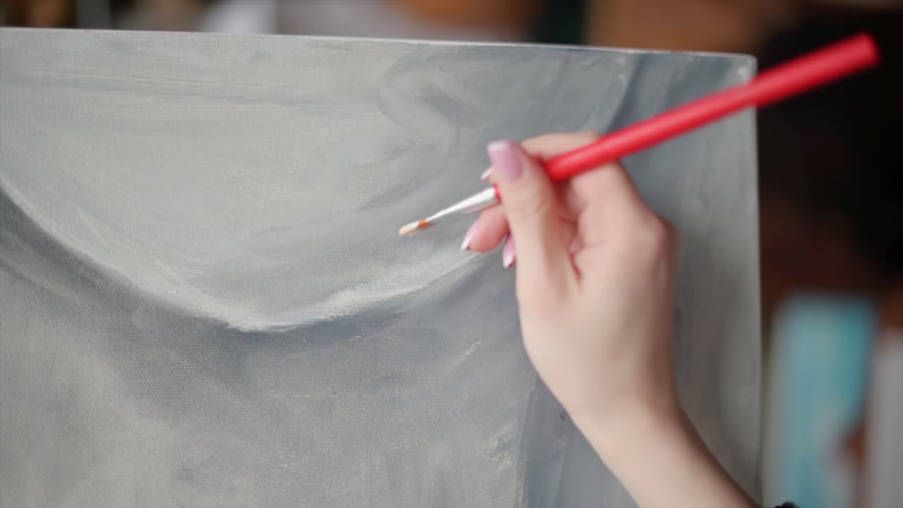 Close up of a woman painting a female body on a canvas at an art gallery workshop
